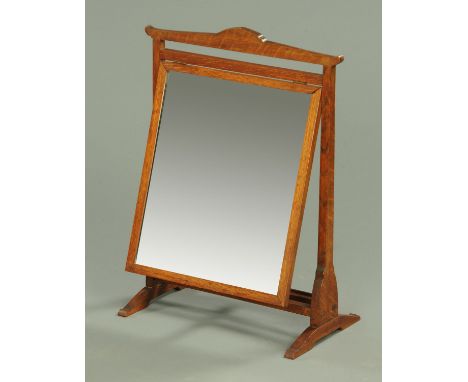 An Arthur W Simpson attributed of Kendal oak framed toilet mirror, with typical joints to the mirror frame and raised on uptu