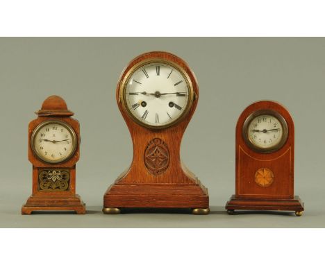 An oak balloon shape mantle clock, with two train movement and supported upon squat brass bun feet, a miniature longcase styl
