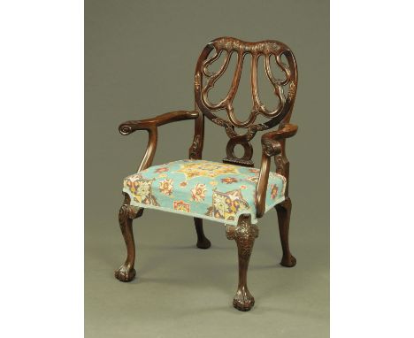 A large Edwardian mahogany armchair, with scroll and bellflower carved pierced back, outswept arms with scroll terminals and 