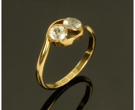 An 18 ct gold crossover ring, set with two clear stone, size K/L.