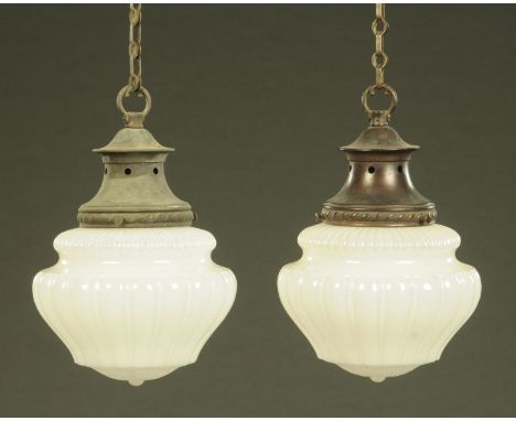 A pair of Edwardian moulded milk glass hanging light shades, with patinated brass suspension mounts, the reeded body above th