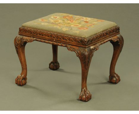 A Queen Anne style oak stool, with floral woolwork top, with carved frame and raised on cabriole legs terminating in claw and