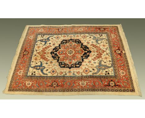 A Persian design fringed carpet, principal colours red, blue and beige, with centre rectangular panel and multiple line borde