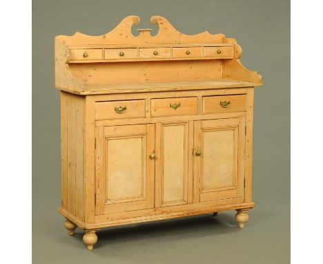 A Victorian stripped pine Scotch kitchen dresser, with swans neck pediment above a series of spice drawers, the base fitted w