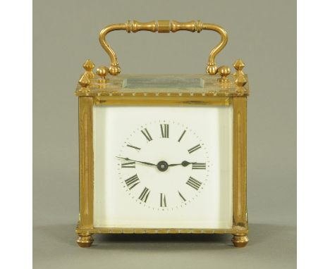 An early 20th century French brass carriage clock, with pointed finials and enamel dial with Roman numerals supported upon sq