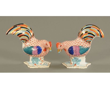 A pair of Herend porcelain cockerels, 20th century, each with a small ball of grain in its mouth and upon a leaf shaped base 