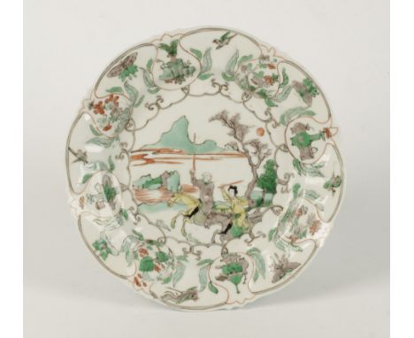 A CHINESE FAMILLE VERTE PLATE, Kangxi (1662-1722), of shaped circular form, centrally painted with a couple on horseback chas