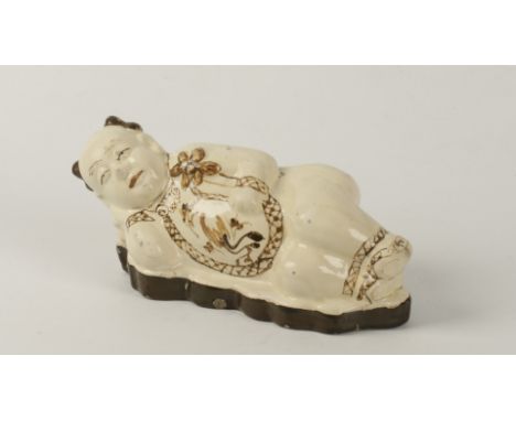 A CHINESE CIZHOU FIGURAL PILLOW, Song Dynasty, as a recumbent boy with floral chest decoration, holding a lotus flower, 28cm 