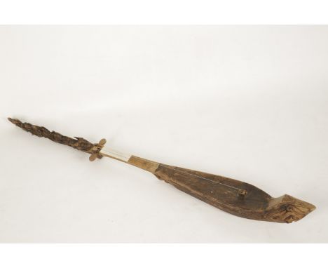 AN INDONESIAN LUTE (HASAPI), late 19th/early 20th century, of boat shape, carved with a mask amongst scrolls, the head with f