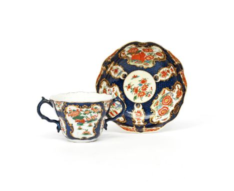 A Worcester two-handled chocolate cup and saucer, c.1775, of ogee-moulded form, painted with panels of Oriental flowers in th