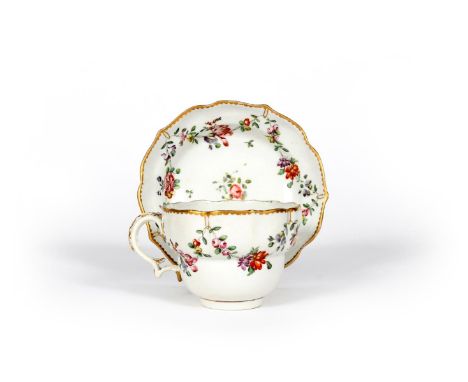A Bristol chocolate cup and saucer, c.1770, of ogee shape, painted with polychrome flower garlands suspended from gilt rings 
