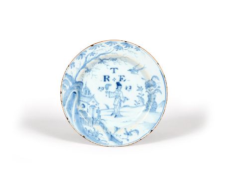 A delftware plate, dated 1742, probably London, painted in blue with a Chinese lady holding a fan and standing between a larg