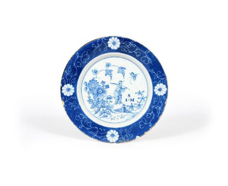 A Lambeth delftware plate, dated 1748, painted in blue with a Chinese figure holding a long feather or leaf frond and walking