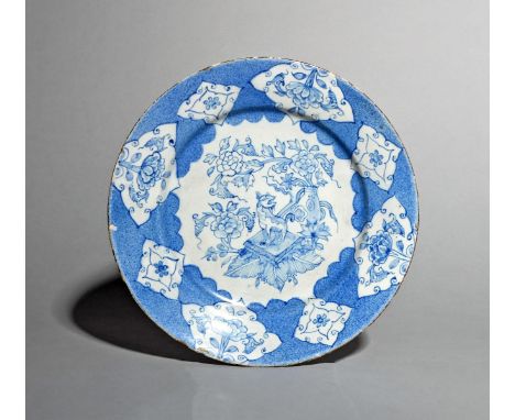 A Liverpool delftware plate, c.1760, painted in blue with a kylin seated on a square cushion before a vase containing floweri