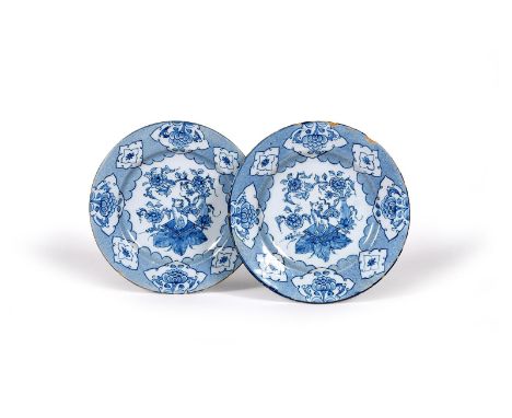 A pair of delftware plates, c.1760, each painted in blue with a kylin seated on a square cushion before a vase containing flo