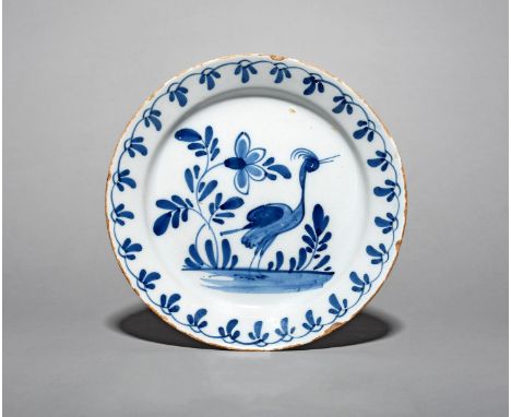 A delftware plate, mid 18th century, probably Bristol, painted in blue with a standing crane or heron beside tall flowering p