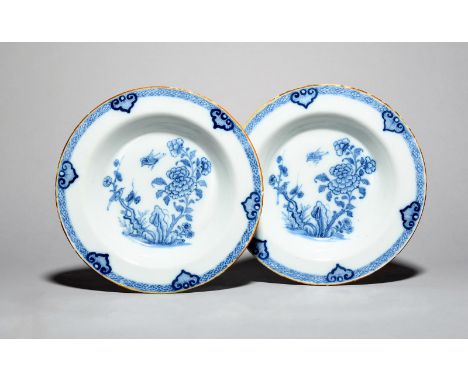 A pair of delftware soup plates, c.1760, each painted in blue with a bird in flight above peony and rockwork, another bird pe