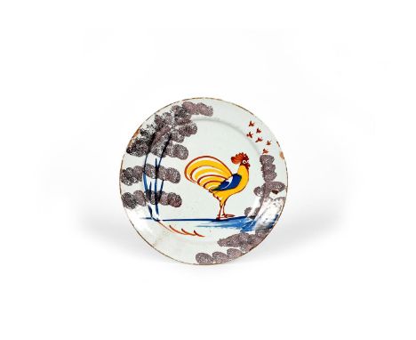 A Bristol delftware 'Farmhouse' plate, c.1720-30, painted with a bold cockerel in yellow, blue and red, standing between spon