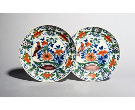 A pair of delftware plates, c.1710-20, possibly London, painted in blue, green, red and manganese, each with a bird perched o