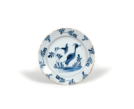A delftware plate, c.1730, naively painted in blue with a large bird standing with beak agape beside simple flowering plants,