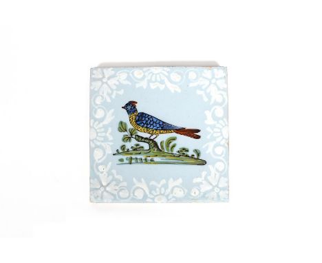 A Bristol delftware bird tile, c.1760, decorated with a bird perched on a stump, painted in red, blue and yellow within a man