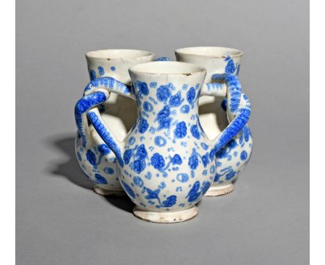 A London delftware fuddling cup, c.1710, formed of three thistle-shaped cups joined by interlocking handles, the bodies paint