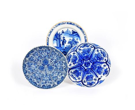 Three Delft chargers, 18th century, one fluted and painted with a dense foliate design, another painted with a panelled desig