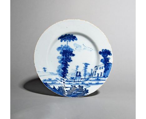 A Bristol delftware plate, c.1760, of Bowen type, painted in blue with two ladies promenading in a European landscape before 
