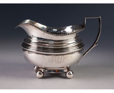 GEORGE III NEWCASTLE SILVER CREAM JUG with gadrooned rim and angular handle, standing on four ball feet, by John Robertson II