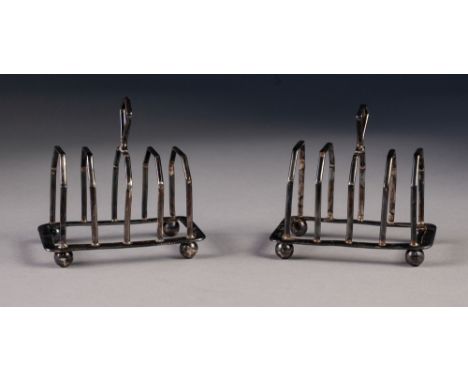 A PAIR OF 1920's SMALL FOUR DIVISION SILVER TOAST RACKS, of angular form with raised handles and ball feet, Adie Bros. Birmin