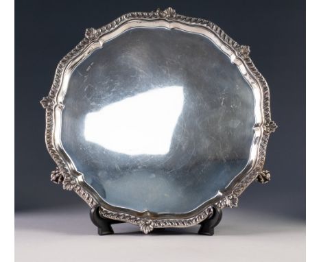 EARLY 20th CENTURY SILVER SALVER with shaped shell work border, standing on three claw feet, Sheffield 1913, 13" (33cm) diame
