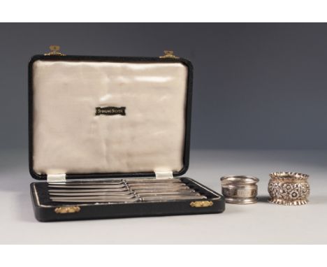 TWO SILVER NAPKIN RINGS, one scroll engraved, the other floral embossed, together with a CASED SET OF SIX AFTERNOON TEA KNIVE