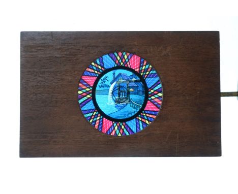 Mahogany-Mounted Magic Lantern Slides,  hand-coloured rackwork slides - lakeside windmill at night with geometric surround, m