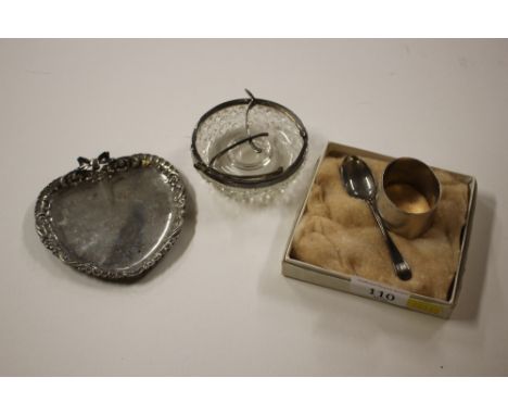 A silver serviette ring with engine turned decoration; a small silver spoon; a silver rimmed and glass dish; and a white meta