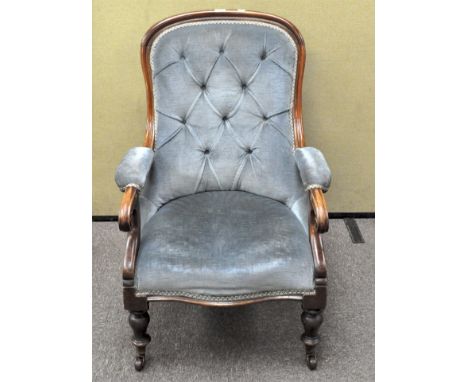 A Victorian mahogany button back armchair, raised on turned supports with castors to front, 93cm high