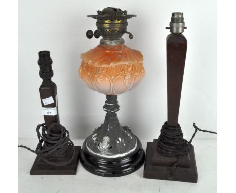 A late 19th/early 20th century oil lamp with vaseline glass reservoir, 41cm high, together with two wooden candlesticks