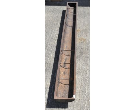 A large metal low feeding trough on feet, 273 cm long 