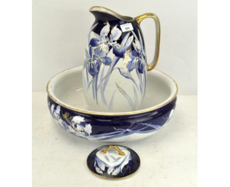 An early 20th century pottery ewer, wash basin and soap dish and cover, decorated with blue orchids with gilt hints, on a whi