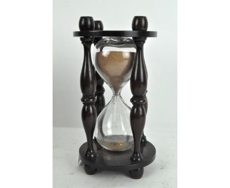 A vintage glass timer, with turned supports and wooden mount, 21cm high
