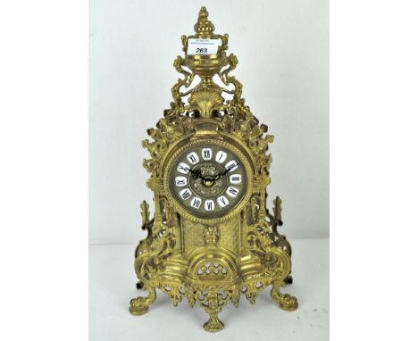An ornate gilt brass quartz mantle clock, the enamel and gilt dial with Roman numerals denoting hours, 42cm high