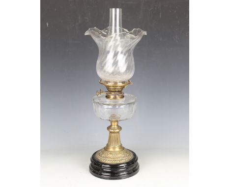 A late Victorian clear cut glass and pressed brass table oil lamp with a clear glass shade and black glazed ceramic base, hei