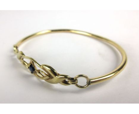 A 9ct yellow gold bangle set a single small sapphire in an openwork setting, 9.7 gms