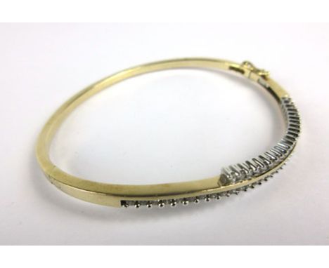A 9ct yellow gold bangle set two rows of small diamonds in a wave type setting, 12.6 gms