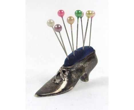 A metalware pin cushion in the form of a heeled shoe, stamped 'Sterling', l. 5.5 cm