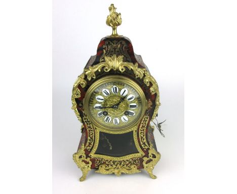 A French boule and gilt brass mounted mantle clock with torch finial above the face with enameled Roman numerals, h. 33 cm, w
