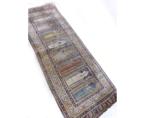 A handwoven silk Persian prayer runner, the multi lined border enclosing a row of eight mihrab each with a hanging mosque lam