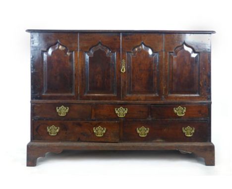 A mid 18th century oak mule chest later converted to a cabinet, the paneled top over four raised fielded, ogee topped panels,