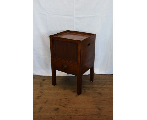 A Georgian mahogany commode with tray top above a tambour slide and pull-out lower section with central circular aperture and