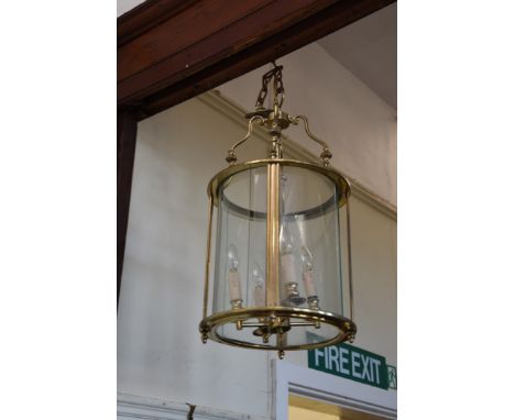 A brass lantern with four simulated candle sconces and curved glass panels.  14½ins diameter.  Est £30-50