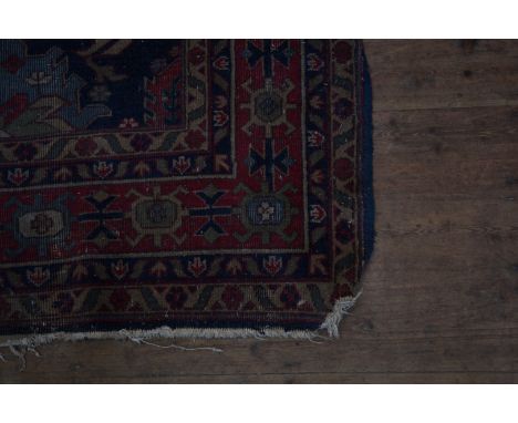 A Middle Eastern carpet, the blue ground with stylised flower heads and leaf decoration to the central field surrounded by mu
